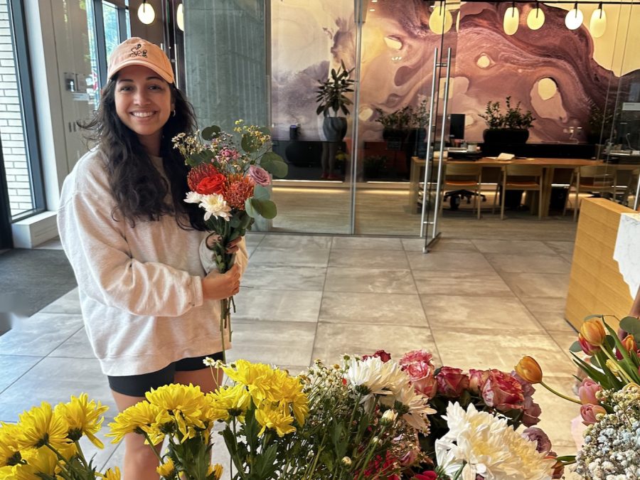 Mariah of Olive Co. holding a fresh bouquet beside a flower cart