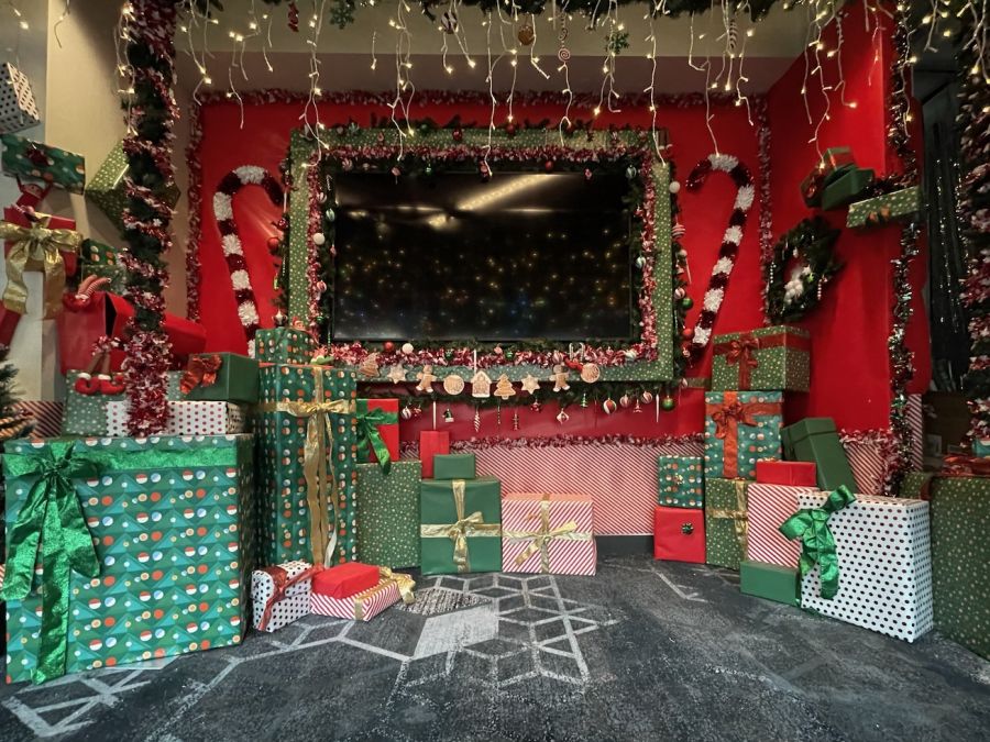 Oversized wrapped gifts and candy canes around a holiday TV wall
