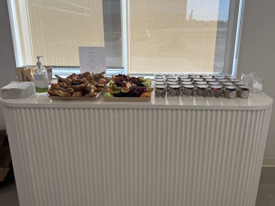Breakfast bar on a white fluted cart with pastry and fruit platters and grab-and-go cups
